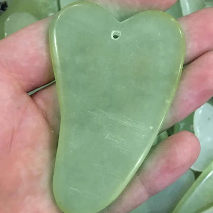 Natural green jade beauty massager with roller and scraper tools on white background
