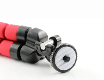 Black flexible octopus tripod with legs wrapped around a pole, holding a smartphone with a clip mount.