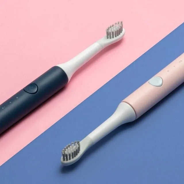 SOOCAS sonic electric toothbrush in blue or pink with round brush head on a bathroom counter.