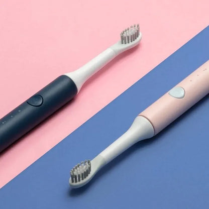 SOOCAS sonic electric toothbrush in blue or pink with round brush head on a bathroom counter.