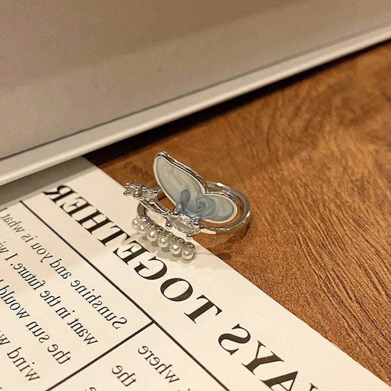 Copper butterfly women's ring with an open loop design on a plain background.