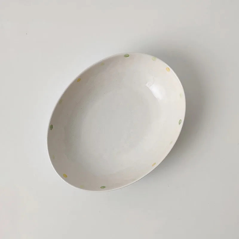 Japanese-style dot pattern porcelain plates and bowls in irregular oval and round shapes on a table.