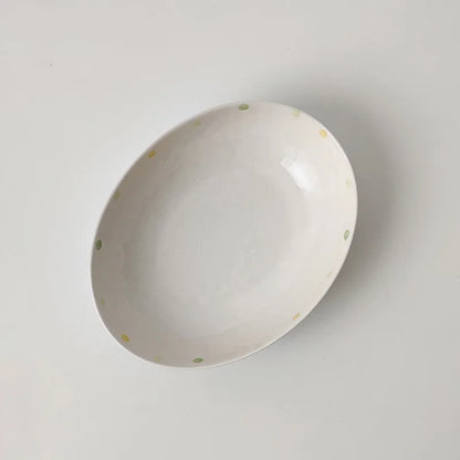 Japanese-style dot pattern porcelain plates and bowls in irregular oval and round shapes on a table.