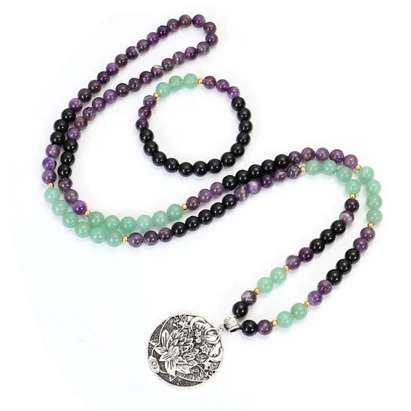 Long stone bead necklace with alloy lotus pendant and matching bracelet set on a background.