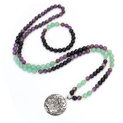 Long stone bead necklace with alloy lotus pendant and matching bracelet set on a background.
