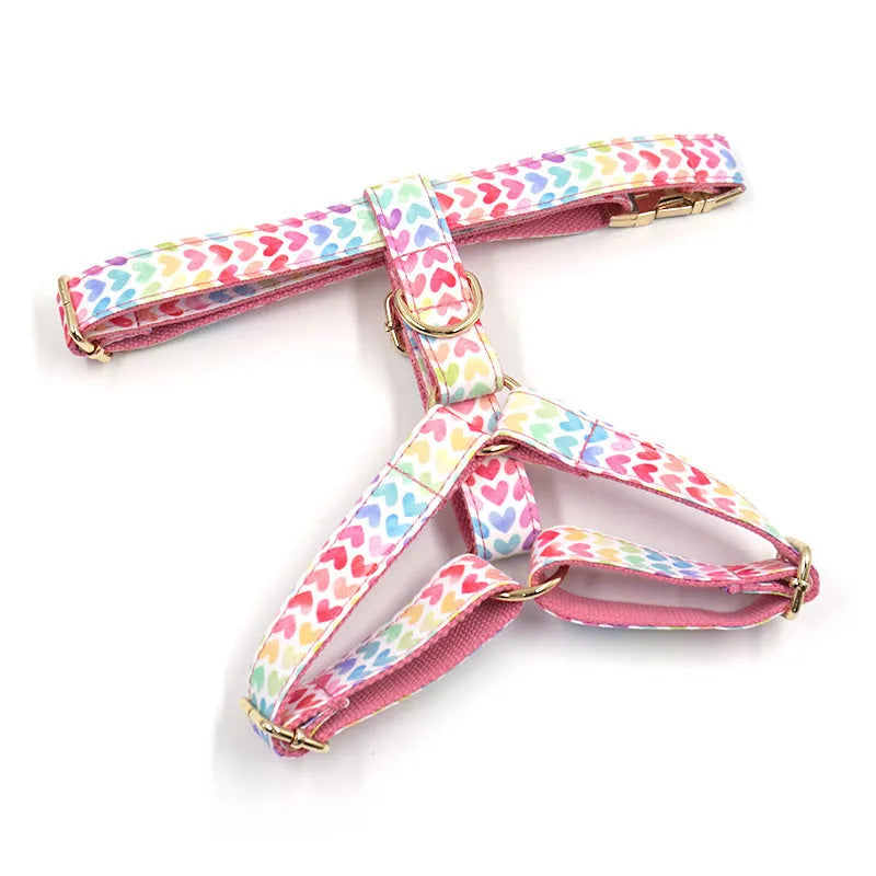 Pink dog harness with gold buckle and heart-shaped stones on a chest and back strap.