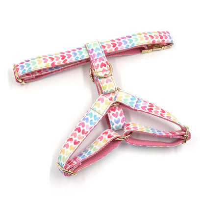 Pink dog harness with gold buckle and heart-shaped stones on a chest and back strap.