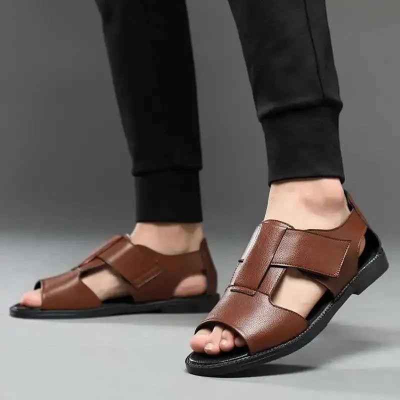 Men's brown leather Roman sandals with an open toe and rubber sole on a wooden surface.