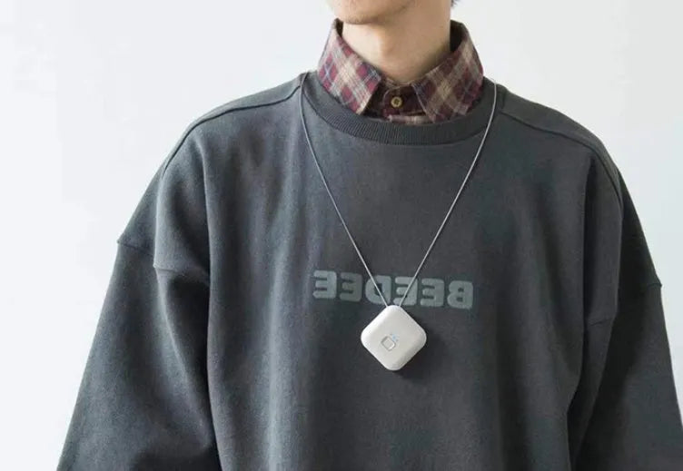Compact pink USB air purifier necklace on a table with charging cable, showing dimensions 1.5 by 5.7 cm.