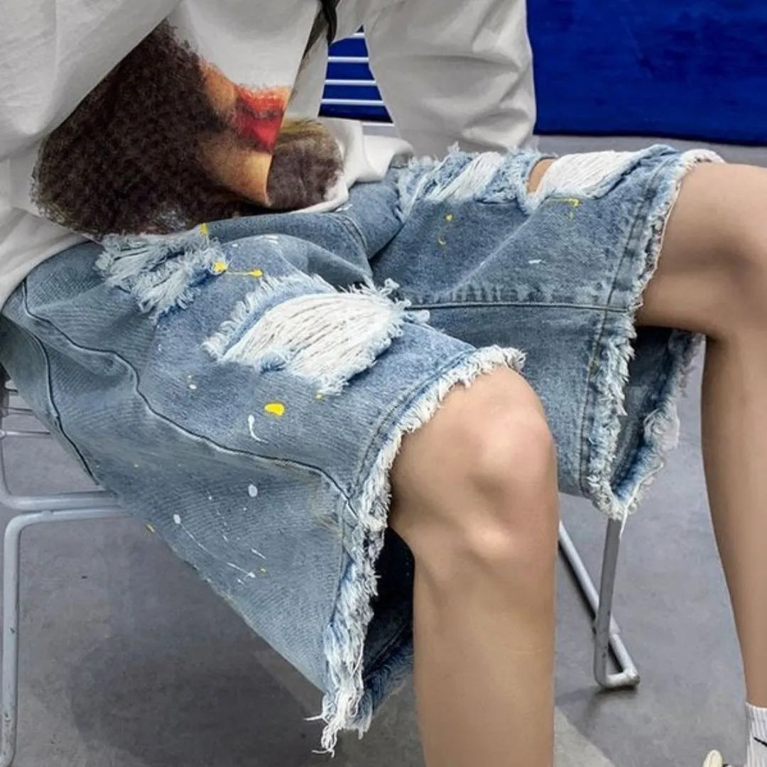 Man wearing loose-fit light blue water-washed denim shorts with a fifth pants length, showing street style.