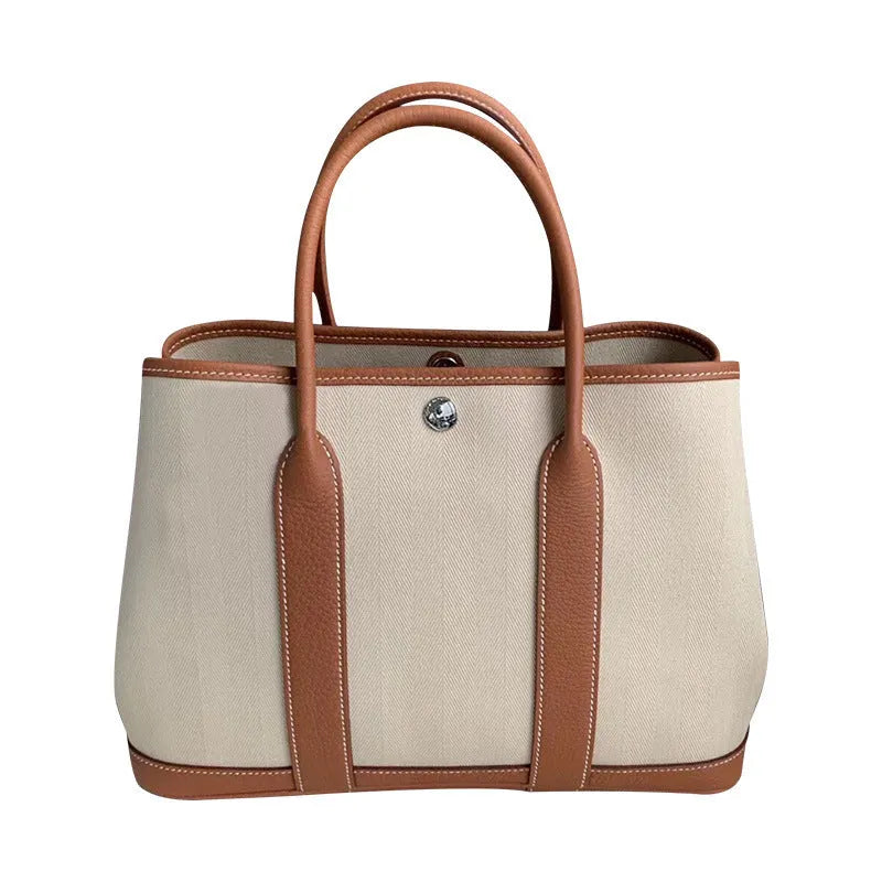 Canvas and leather tote bag in bucket shape with crossbody strap, shown in black, brown, gray or red colour options