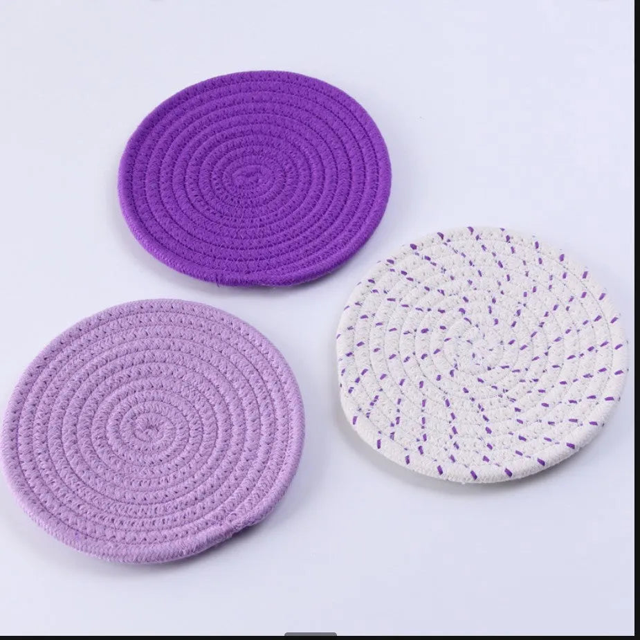 Three round grey cotton cord coaster placemats on a wooden table, each 18cm in diameter.