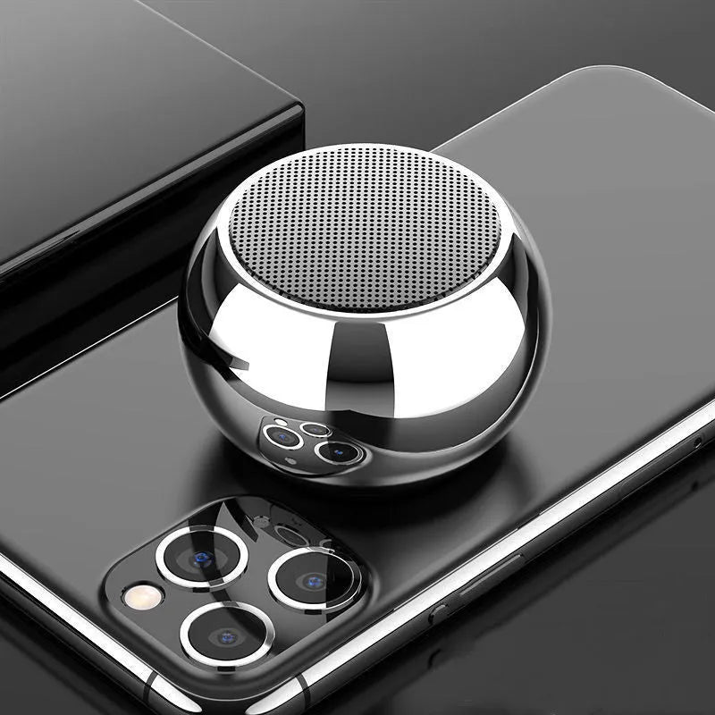 Small round aluminium Bluetooth speaker in gradient blue, showing compact size next to a USB cable.
