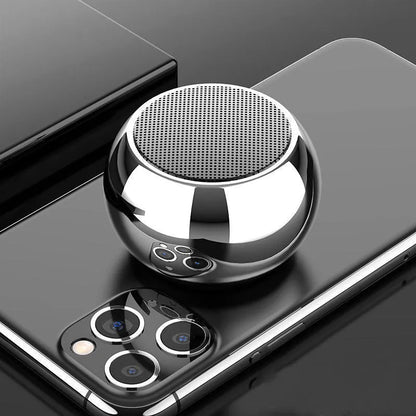 Small round aluminium Bluetooth speaker in gradient blue, showing compact size next to a USB cable.