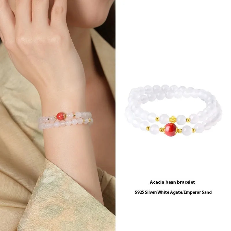 Close-up of a women's double layer bracelet with polished white agate and jequirity bean beads.