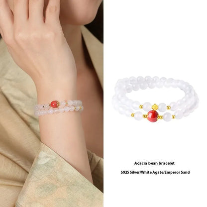 Close-up of a women's double layer bracelet with polished white agate and jequirity bean beads.