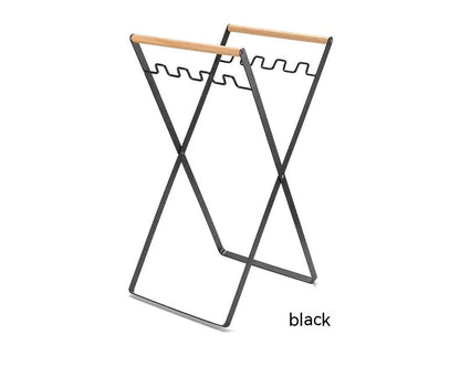 Black outdoor folding trash rack with wooden handle, holding a waste bag.