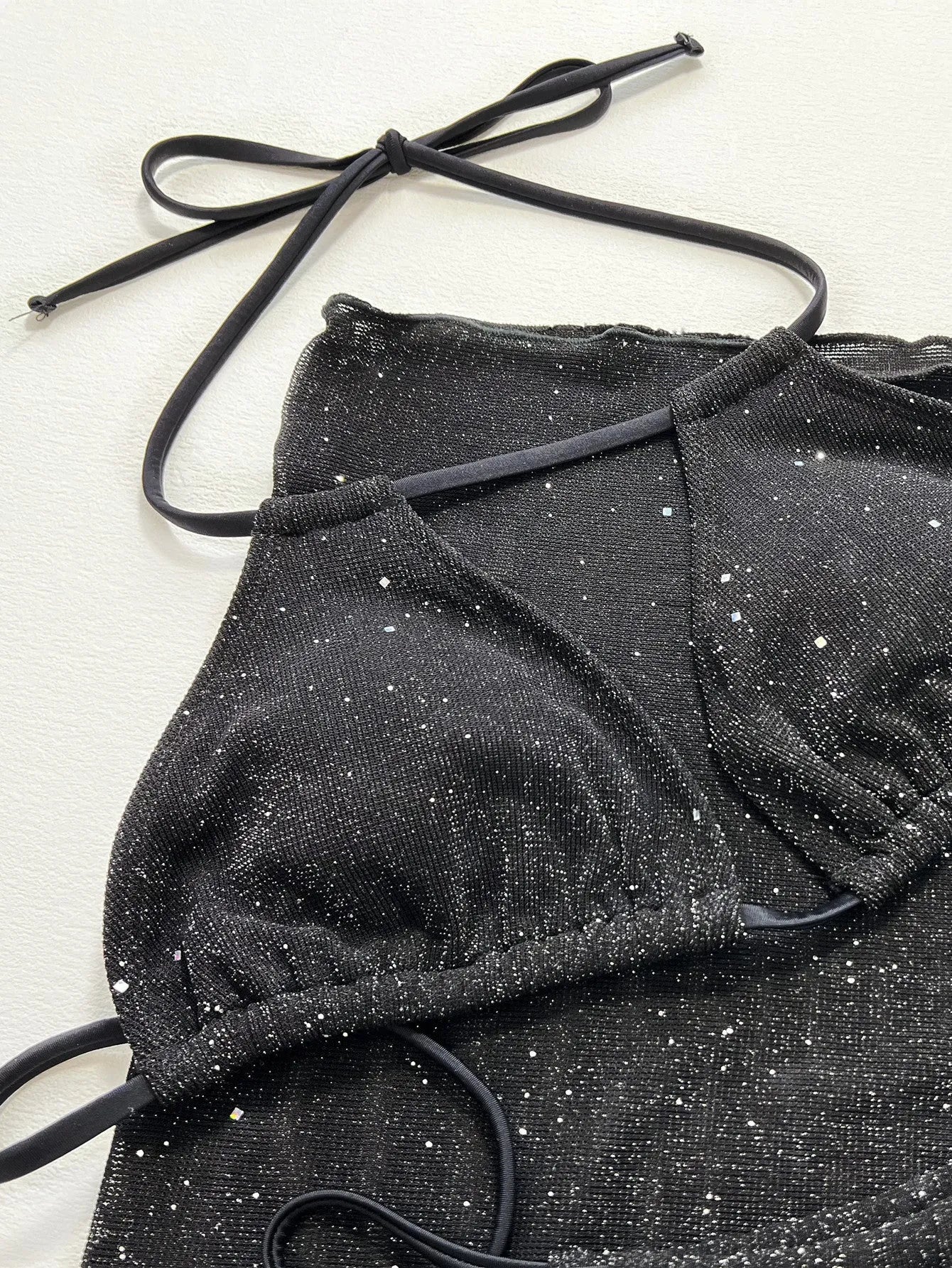 Black three-piece fission style swimsuit bikini set with top and shorts on a mannequin.