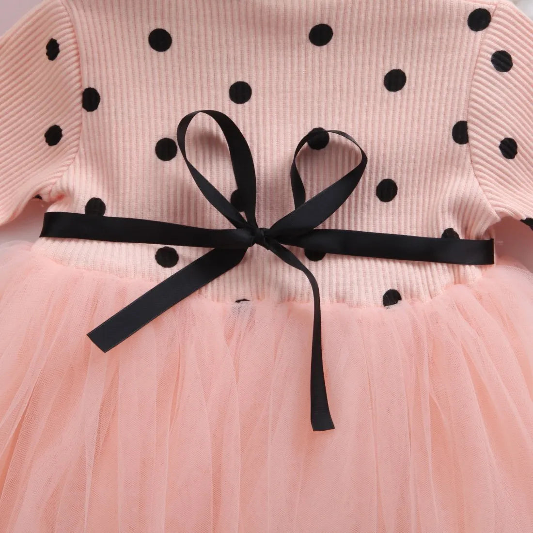 Baby girl wearing a long sleeve black tutu dress with lace detail for a birthday party.