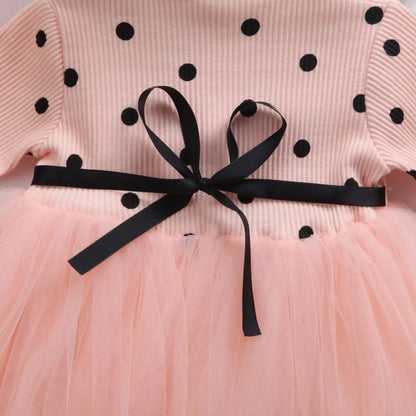 Baby girl wearing a long sleeve black tutu dress with lace detail for a birthday party.