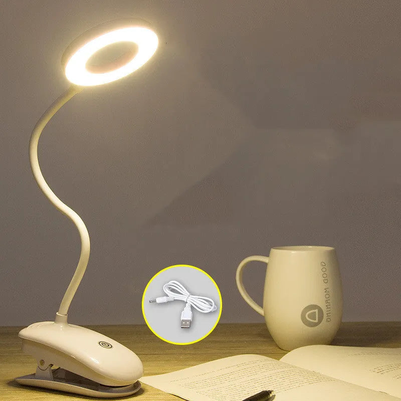 A modern white clip-on rechargeable desk lamp with a touch-sensitive switch and a plastic shade.