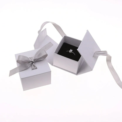 Grey square jewellery box with white ribbon bow measuring 5x5x4cm with sponge-lined interior