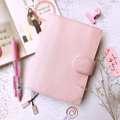 Close-up of a hand-embossed lychee pattern on an off-white A6 cowhide leather notebook with loose-leaf binding.
