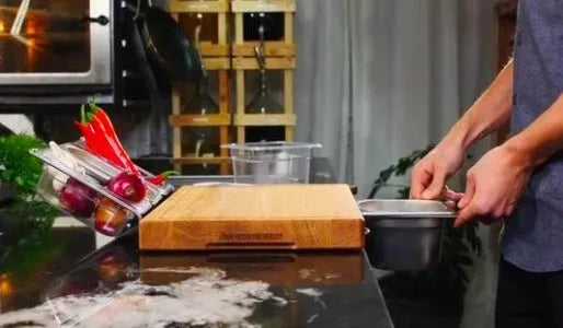 Bamboo cutting board with smooth surface alongside two large and three small plastic storage trays for vegetables and meat.