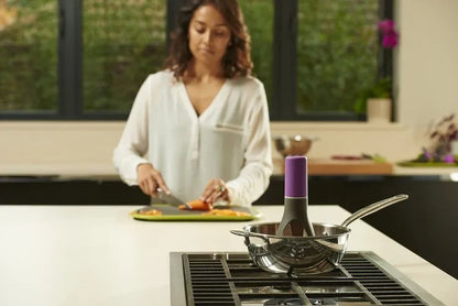 Green Uutensil Stirr automatic pot stirrer device standing next to a saucepan on a kitchen counter