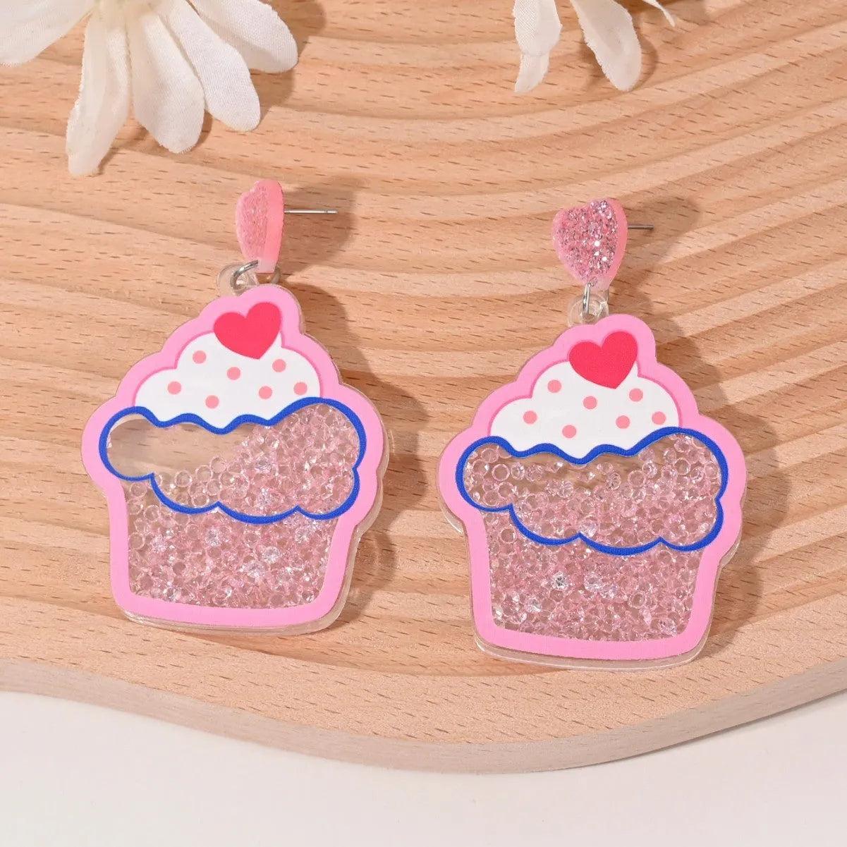 A pair of colourful acrylic earrings shaped like a strawberry and a cherry on a woman's ear.