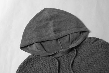 A man wearing a cotton-polyester blend hoodie available in nine colours including black, navy, and red.