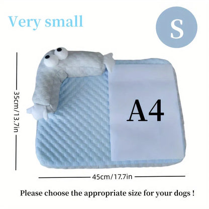 Blue pet bed cushion with big-eyed monster design, shown on a wooden floor.