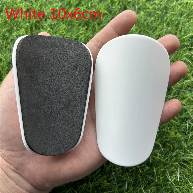 Extra small 8x5cm black and white plastic football shin guards for junior players.