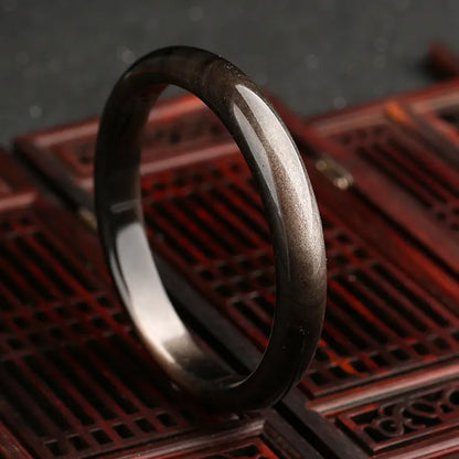 Natural silver cat's eye stone bracelet with geometric ethnic design on a wrist.