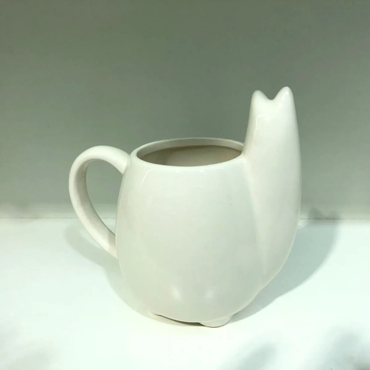 White ceramic mug with cartoon alpaca pattern and handle