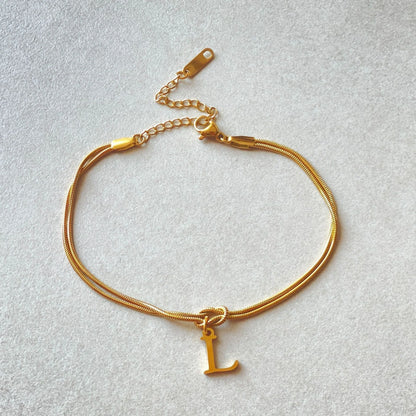 Elegant letter charm bracelets for women in gold and silver tones, featuring a delicate snake chain design and personalised letter charms.