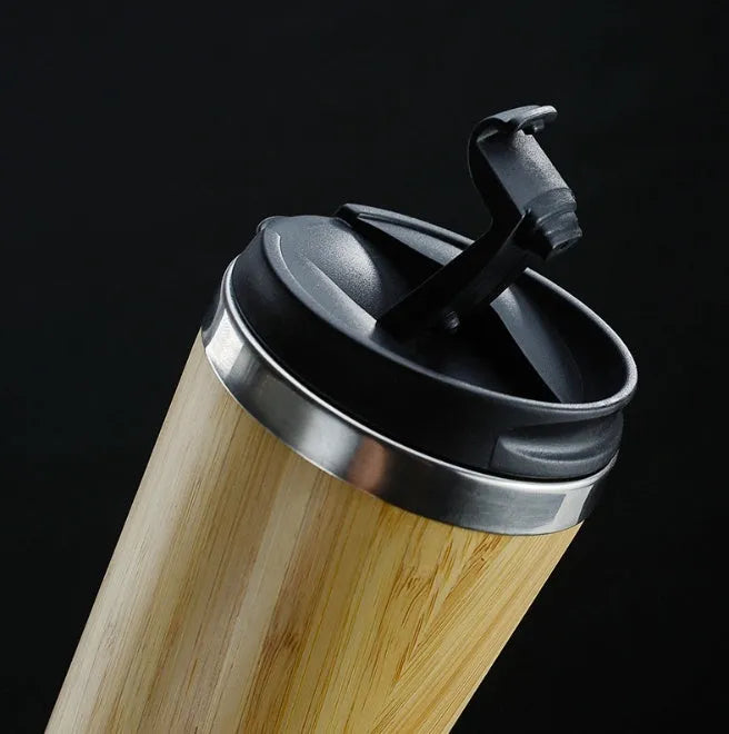 Natural bamboo fibre and stainless steel reusable travel coffee cup with black leak-proof lid on a table