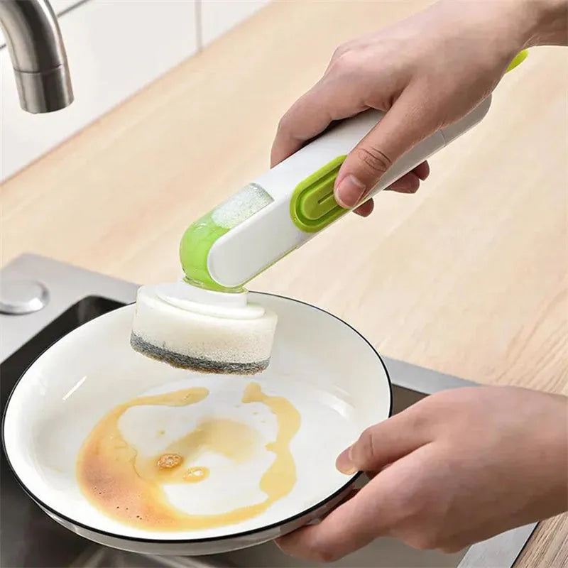 White and red long-handle kitchen brush with soap dispenser button and two interchangeable scrub heads on a hook.