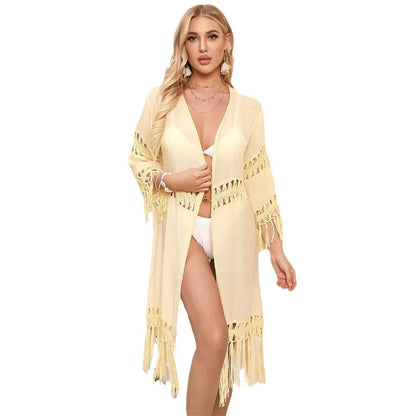 Yellow hand-crocheted acrylic beach cover-up cardigan with tassels, laid flat on a sandy background.