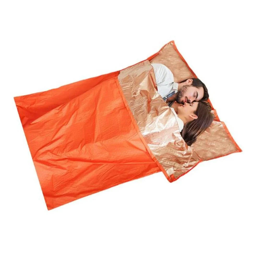 Orange outdoor thermal sleeping bag with silver coated nylon showing envelope design and storage bag