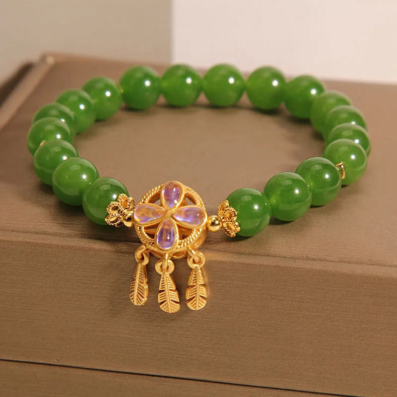 Green jasper crystal four-leaf clover dream catcher pendant on a women's bracelet.