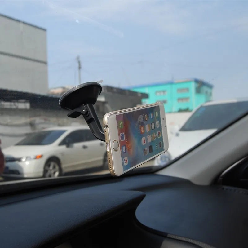 Black magnetic car phone holder with rotating head shown mounted on dashboard