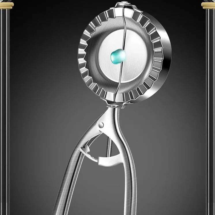 Silver stainless steel manual dumpling press with hinged handles on a wooden kitchen surface.