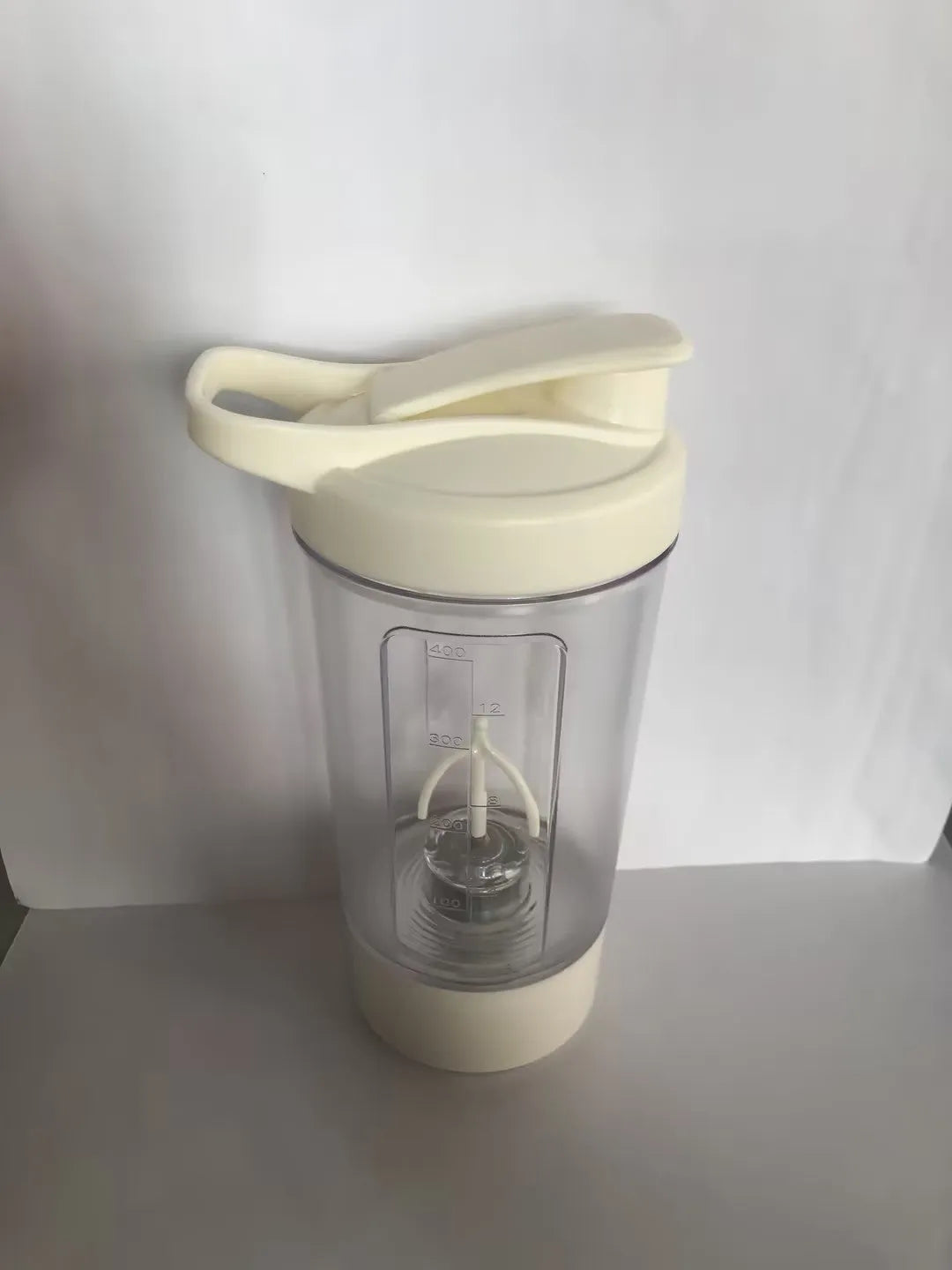 Black electric protein shaker cup with lid on a gym towel, showing USB charging port.