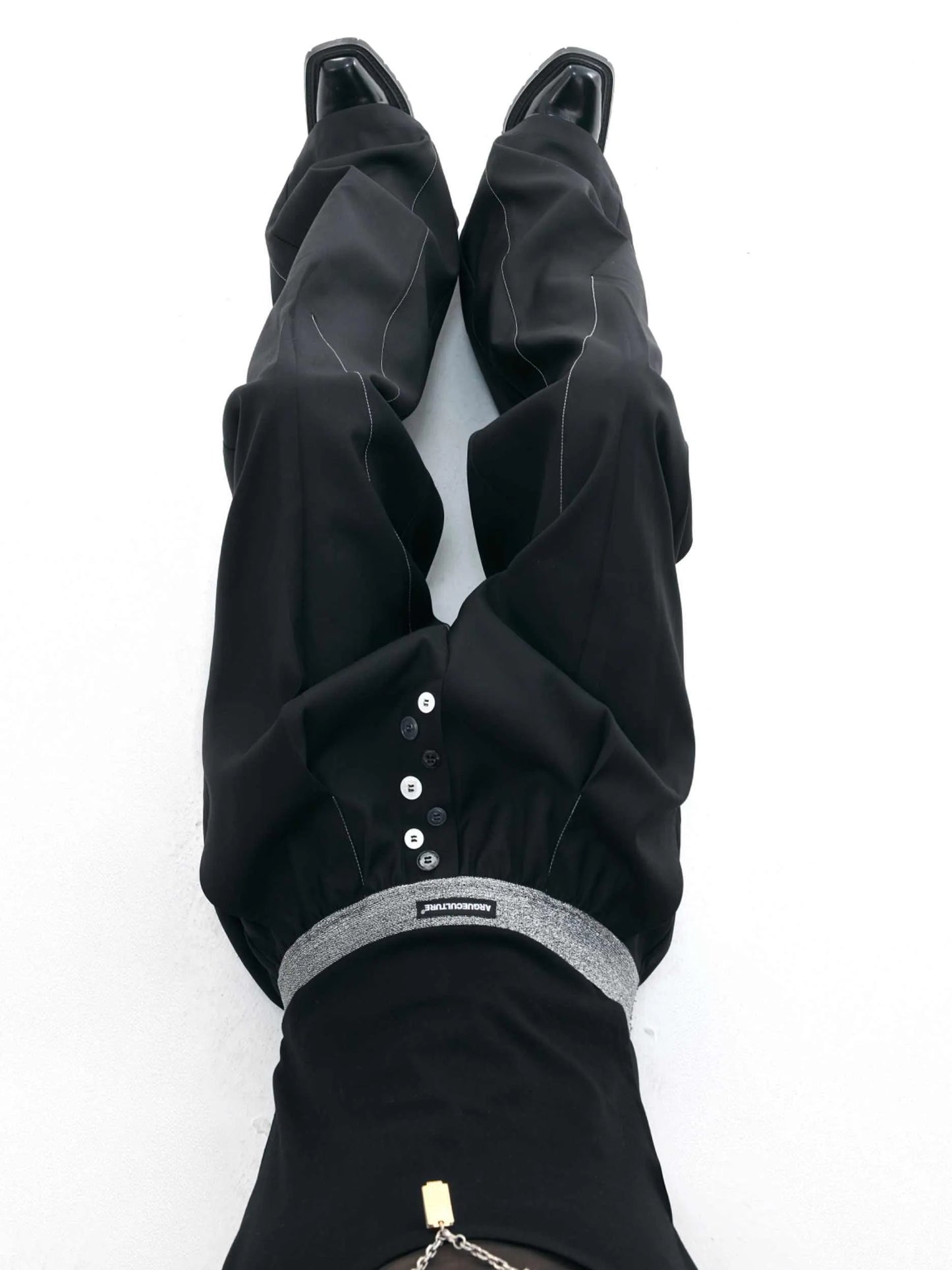 Straight-leg trousers with button-open line detail in black and grey colours, showing high-waist design and tailored silhouette
