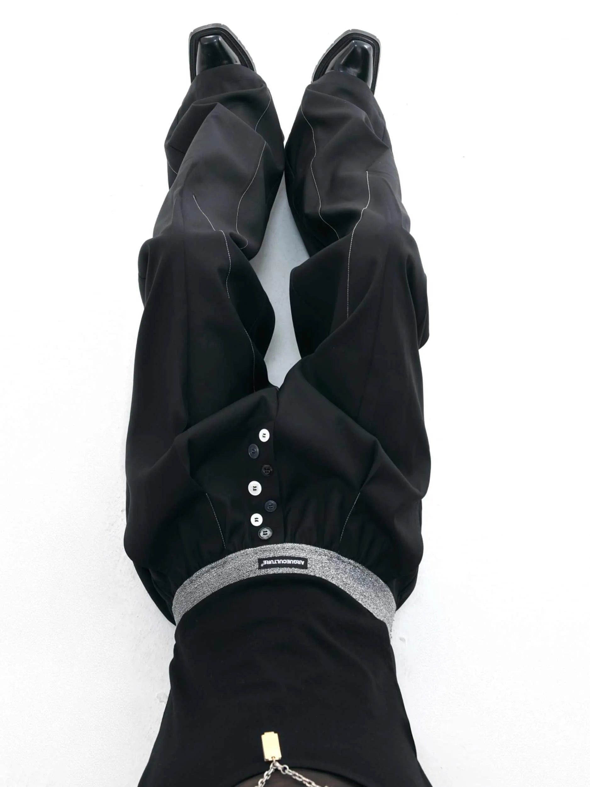 Straight-leg trousers with button-open line detail in black and grey colours, showing high-waist design and tailored silhouette
