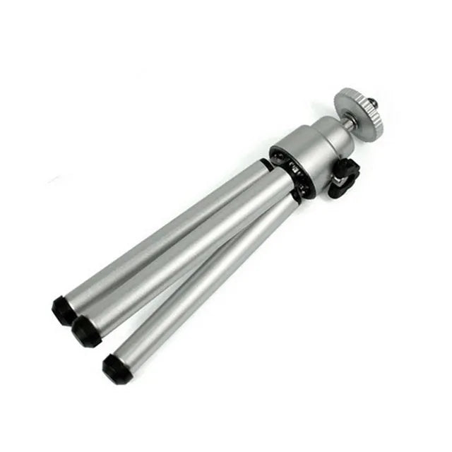 Black mini camera tripod with extended legs and a separate U-shaped universal phone clip on a table.