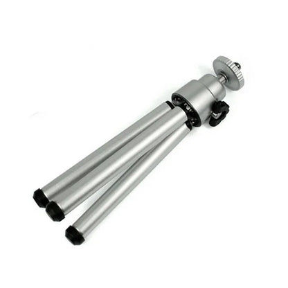 Black mini camera tripod with extended legs and a separate U-shaped universal phone clip on a table.
