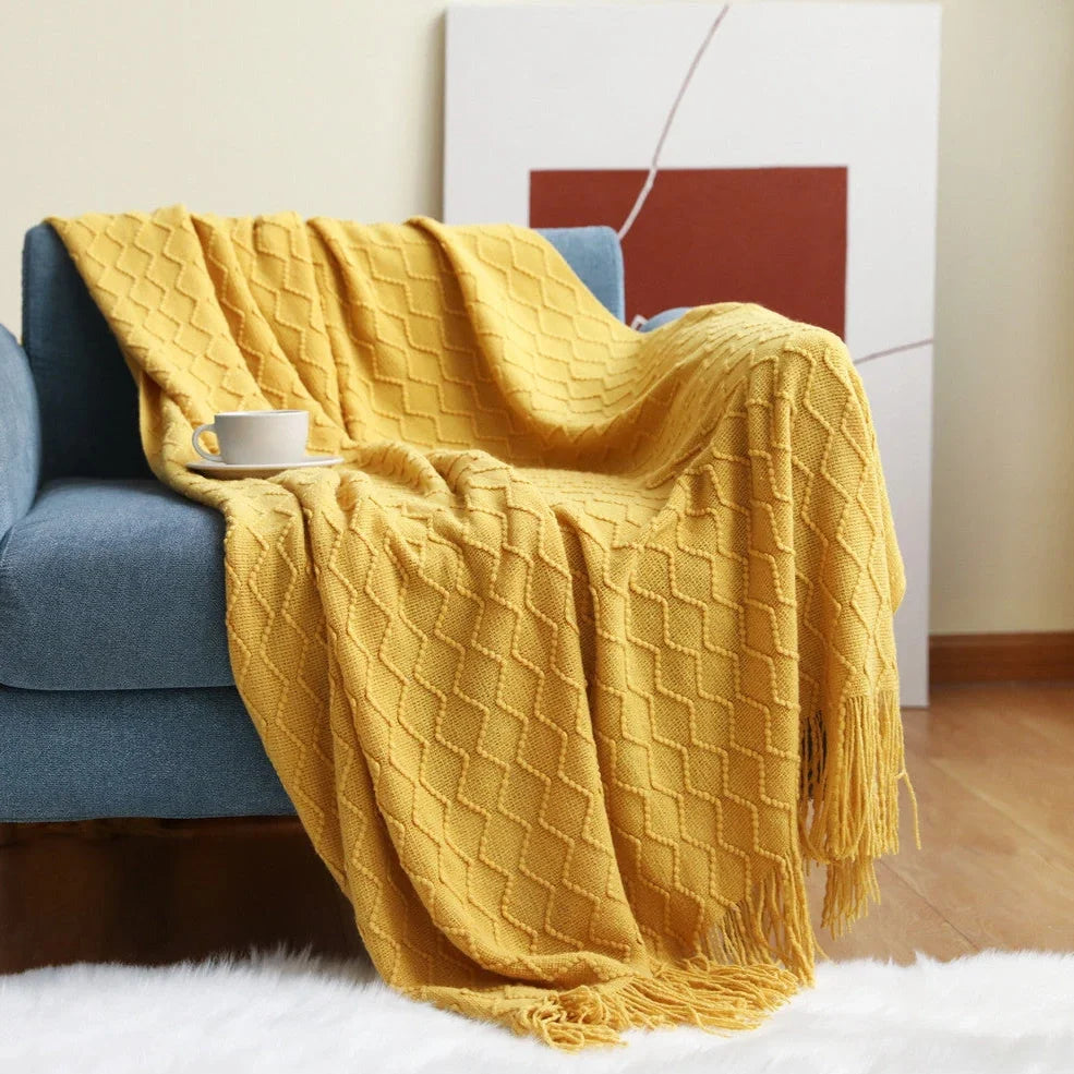 Nordic knitted blanket in beige colour showing open knit pattern on grey sofa