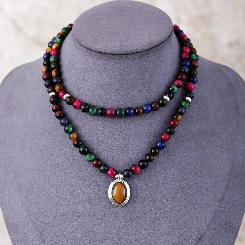 Coloured tiger-eye natural stone bead necklace and bracelet set with 108 gem-inlaid pendants on a dark background.